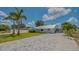 Charming single-story home with fresh landscaping and a gray brick driveway under a blue sky with clouds at 1461 Porpoise Rd, Venice, FL 34293