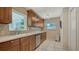 Well-lit kitchen featuring wooden cabinets, stainless steel dishwasher, and mosaic backsplash at 1461 Porpoise Rd, Venice, FL 34293