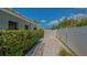 Side yard with white fence, gravel, mature landscaping, and potential for storage or utilities at 1461 Porpoise Rd, Venice, FL 34293