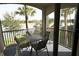Screened patio with a table and chairs, offering views of the lake and swaying palm trees at 16904 Vardon Ter # 208, Lakewood Ranch, FL 34211