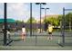 Tennis court with players ready for a friendly match, fence in the foreground, palm trees and house in background at 16904 Vardon Ter # 208, Lakewood Ranch, FL 34211