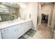 Bathroom featuring double sinks, white cabinets, and an entrance to the closet at 18008 Waterville Pl, Bradenton, FL 34202