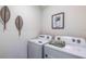 Laundry room with a side-by-side washer and dryer, decorative wicker wall art, and a succulent plant print at 18313 Canopy Pl, Lakewood Ranch, FL 34211