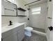 Updated bathroom features modern fixtures, tiled shower, gray vanity, and decorative black shelving at 1902 24Th W Ave, Bradenton, FL 34205