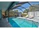 Relaxing screened-in pool area with lounge chairs, a grill, and a dining table for outdoor enjoyment at 2127 Corfell St, Port Charlotte, FL 33948