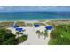 Beautiful beach with blue cabanas, white sand, and clear blue water, surrounded by green vegetation at 3060 Grand Bay Blvd # 182, Longboat Key, FL 34228