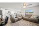 Inviting living room with a ceiling fan, two sofas and rug, adjacent to kitchen with white cabinets at 3108 Rock Sound St, Bradenton, FL 34208