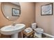 Cozy powder room with a pedestal sink, round mirror, and soft lighting, creating a warm and inviting space at 3210 Bitterroot Ln, Lakewood Ranch, FL 34211