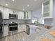 Modern kitchen with white cabinetry, stainless steel appliances, granite countertops, and a breakfast bar area at 3212 Avenue A W, Bradenton, FL 34205
