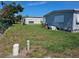 Lush backyard with green grass, utility connections and mobile homes providing a serene outdoor setting at 3212 Oakwood S Blvd, Sarasota, FL 34237