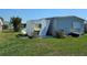Mobile home with a damaged siding and white metal storage shed against the backdrop of a clear blue sky at 3212 Oakwood S Blvd, Sarasota, FL 34237