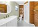 A bathroom with wood paneled walls, a walk-in shower and a white sink at 3934 Brookside Dr, Sarasota, FL 34231