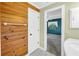 A bathroom with wood paneled walls, entrance to a bedroom and white marble tile floors at 3934 Brookside Dr, Sarasota, FL 34231