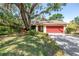 Charming single-story home with a red garage door, mature trees, and a spacious driveway at 3934 Brookside Dr, Sarasota, FL 34231