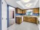 A well-lit kitchen with wood cabinets and tile floors with a view to a carpeted room at 3934 Brookside Dr, Sarasota, FL 34231