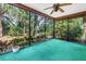 A screened lanai features a ceiling fan, green carpet, and views of the lush backyard at 3934 Brookside Dr, Sarasota, FL 34231
