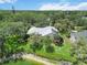 Aerial shot of a home surrounded by mature trees, green lawns, and a small lake at 4443 Robin Hood W Trl, Sarasota, FL 34232