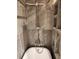 Clawfoot bathtub with gray marble tile, designer fixtures and cubbies for storage in the updated bathroom at 4873 Huntleigh Dr, Sarasota, FL 34233