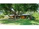 Quaint single story home with yellow exterior, mature trees, and stone accent wall at 4873 Huntleigh Dr, Sarasota, FL 34233