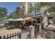 Lovely patio featuring shaded seating with multiple tables and green chairs, surrounded by mature trees at 525 N Orange Ave # 202, Sarasota, FL 34236