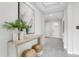 Bright hallway with decorative table, plants and a large painting, leading to the front door at 5770 Long Shore Loop, Sarasota, FL 34238