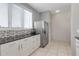 Bright kitchen showcasing stainless steel refrigerator, white cabinets and tiled floor near a bright window at 603 Cedars Ct, Longboat Key, FL 34228