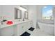 Bright bathroom featuring dual vanities, a sleek soaking tub, modern fixtures, and a window with neighborhood views at 6146 Grandeur St, Englewood, FL 34224