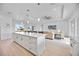 Open kitchen and living space with a large center island, modern lighting, and stainless steel appliances at 6146 Grandeur St, Englewood, FL 34224