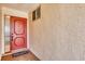 Foyer with a textured wall, a red front door, and a 