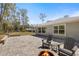 Wide backyard showcasing a blue home with a stone patio with a cozy fire pit and chairs at 6766 Beedla St, North Port, FL 34291