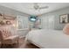A cozy bedroom with white shutters, light pink accent chair, wood-look tile and modern art at 6766 Beedla St, North Port, FL 34291