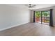 Bright bedroom featuring light wood floors and sliding glass doors with patio views and grey curtains at 709 Sorrento Inlt # 709, Nokomis, FL 34275