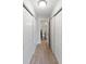 Hallway with closets and light wood floors leading to bathroom with white toilet, vanity and shower at 709 Sorrento Inlt # 709, Nokomis, FL 34275