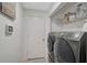 Modern laundry room with front loading washer and dryer and storage shelves at 7118 Lakeside Dr # 7118, Sarasota, FL 34243