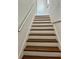 Staircase featuring wooden steps, white risers, and a metal handrail, with bright lighting at 8412 Grove Blvd, Punta Gorda, FL 33982