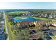 Aerial view of condo buildings with terracotta roofs situated alongside a pristine golf course and lake at 8422 Wethersfield Run # 103, Lakewood Ranch, FL 34202