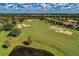 Expansive aerial view of community featuring golf course, sand traps, lush greenery, and pond at 8422 Wethersfield Run # 103, Lakewood Ranch, FL 34202