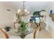 Elegant dining room with glass-top table, chandelier, and a partial view of the living room at 8422 Wethersfield Run # 103, Lakewood Ranch, FL 34202