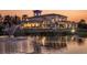 A luxurious home reflected in the peaceful lake with an illuminated fountain at sunset at 8422 Wethersfield Run # 103, Lakewood Ranch, FL 34202