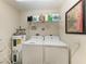 Functional laundry room with washer, dryer, and overhead shelving at 8422 Wethersfield Run # 103, Lakewood Ranch, FL 34202