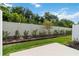 A landscaped backyard featuring a privacy fence, green grass, small trees, and mulch at 9064 Driven Snow St, Sarasota, FL 34241