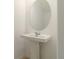Modern bathroom with a pedestal sink, round mirror, and clean, neutral tones at 9064 Driven Snow St, Sarasota, FL 34241