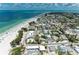 Wide aerial shot displaying beach homes near the ocean, white sands and lush island foliage at 104 Magnolia Ave, Anna Maria, FL 34216