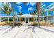 Charming yellow beach house with white trim, surrounded by palm trees and sandy landscape at 104 Magnolia Ave, Anna Maria, FL 34216