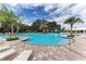 A refreshing community pool area with palm trees, lounge chairs, and a clear blue sky at 10962 High Noon Trl, Parrish, FL 34219