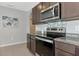 Galley kitchen includes stainless steel appliances and granite countertops with dark cabinets at 12712 Dusty Trail Dr, Sarasota, FL 34238