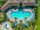 Aerial view of a luxurious community pool with many lounge chairs, umbrellas, palm trees, and manicured landscaping at 12712 Dusty Trail Dr, Sarasota, FL 34238