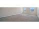 A spacious bedroom featuring neutral carpeting and bright natural light from the two windows at 12732 Lateral Root Dr, Sarasota, FL 34238