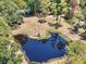 Aerial view of pond surrounded by lush green trees, and beautiful home in a serene landscape at 13719 Seminole Trl, Wimauma, FL 33598