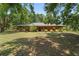 Daytime shot of a charming single-story home with a well-manicured lawn and lush landscaping at 13719 Seminole Trl, Wimauma, FL 33598